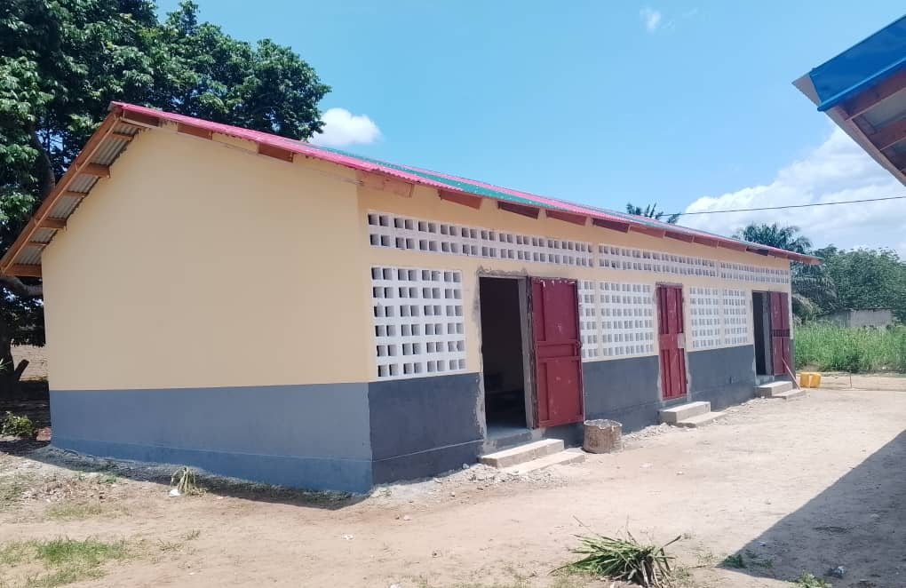 A new single-storey classroom block with red doors, built by a private school along the rehabilitated avenue in Gamboma