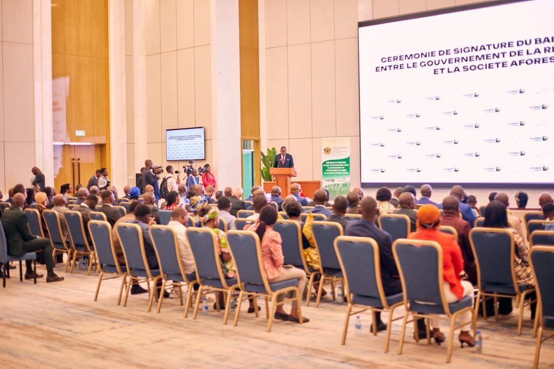 Delegates in a large hall facing the stage at the lease signing ceremony, with the ceremony title on the screen