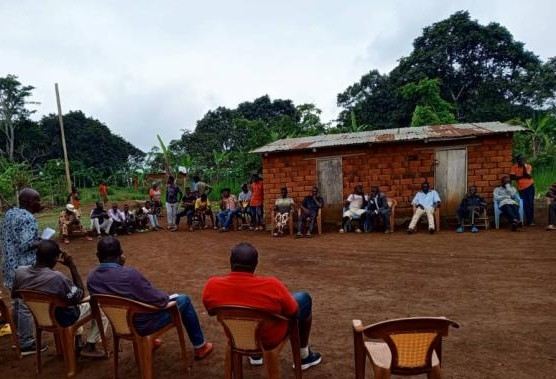 Residents seated in a circle in a village during a consultation